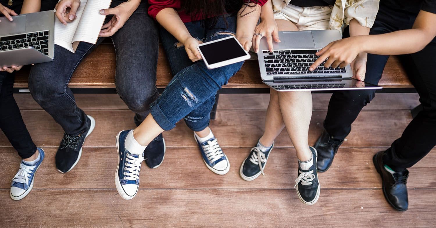 4 Students on campus while using laptops and tablets