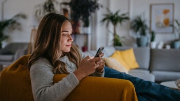 Female college student browsing on a phone while at home