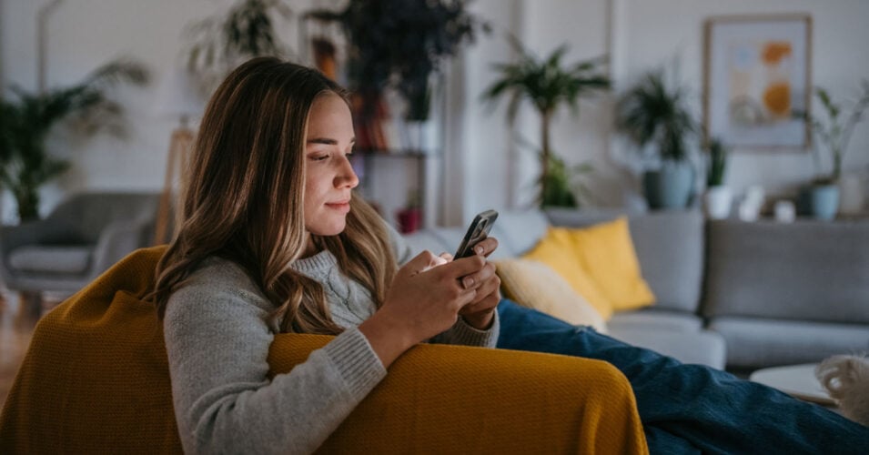 Female college student browsing on a phone while at home