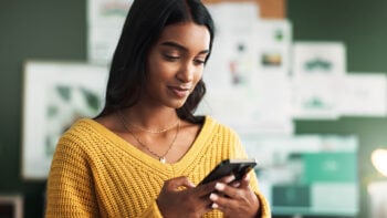 Woman in yellow shirt scrolling on cell phone