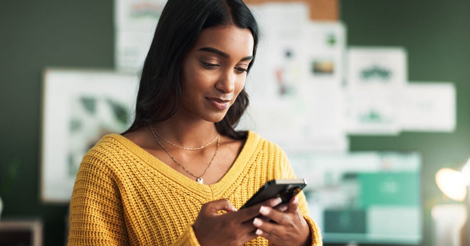 Woman in yellow shirt scrolling on cell phone